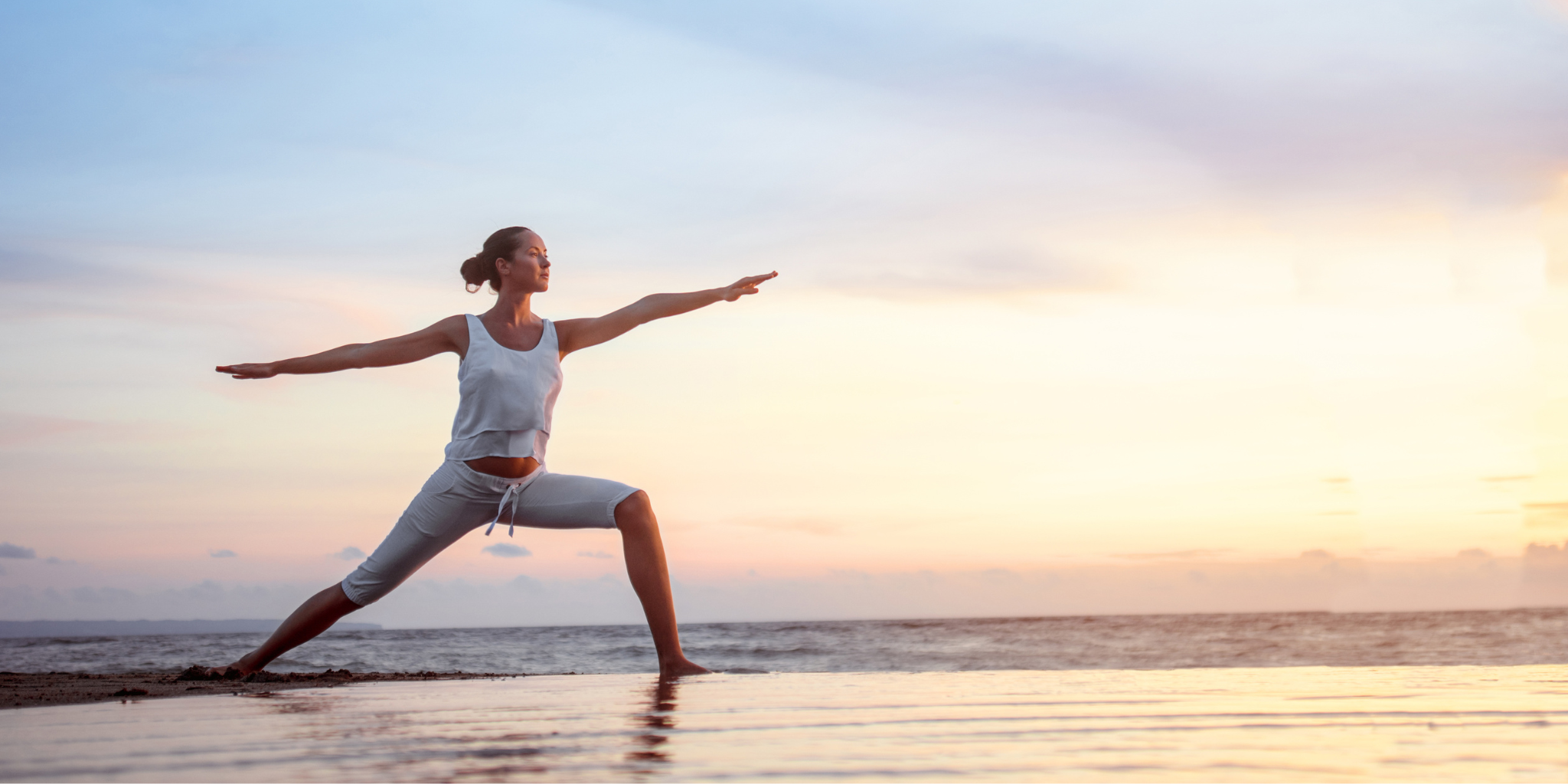 Femme en posture de yoga face au coucher de soleil sur la plage